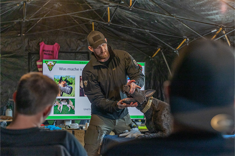 Instructor Marc demonstriert an Hundepuppe Eddy erste Hilfe für Vierbeiner