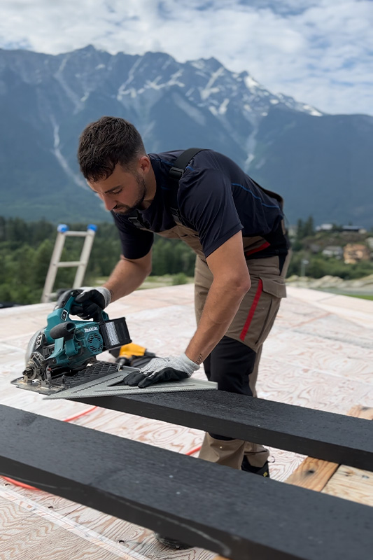 Tarek sägt auf der Baustelle, im Hintergrund die Berge